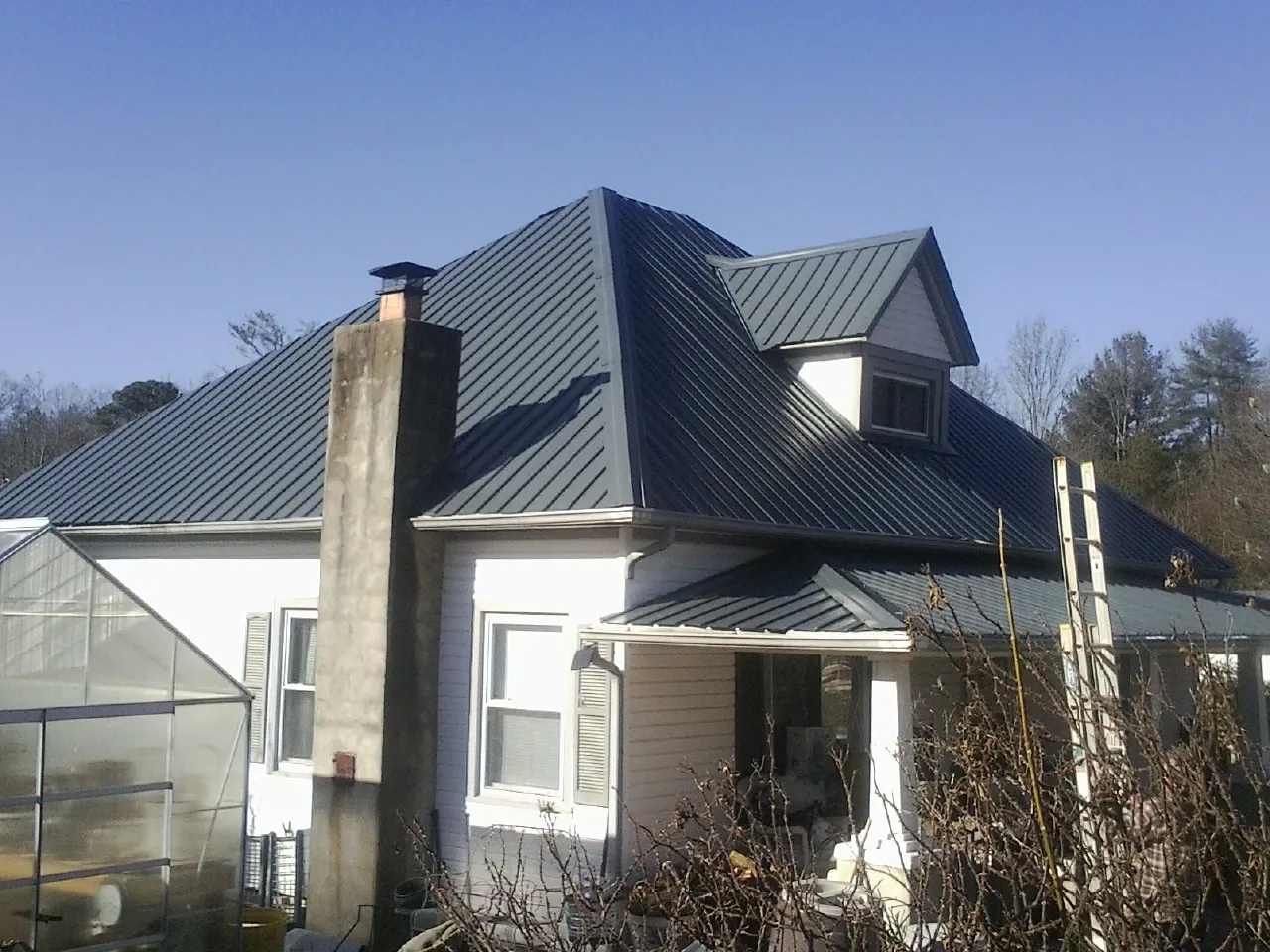 Dark blue standing seam metal roof on a white farmhouse with dormer — Slate & Tile Roof Repair by Roofing Brothers in Hopkinsville