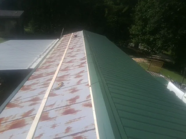 Old rusted panels beside newly installed green metal roofing — Wind Damage Roof Repair by Roofing Brothers in Hopkinsville