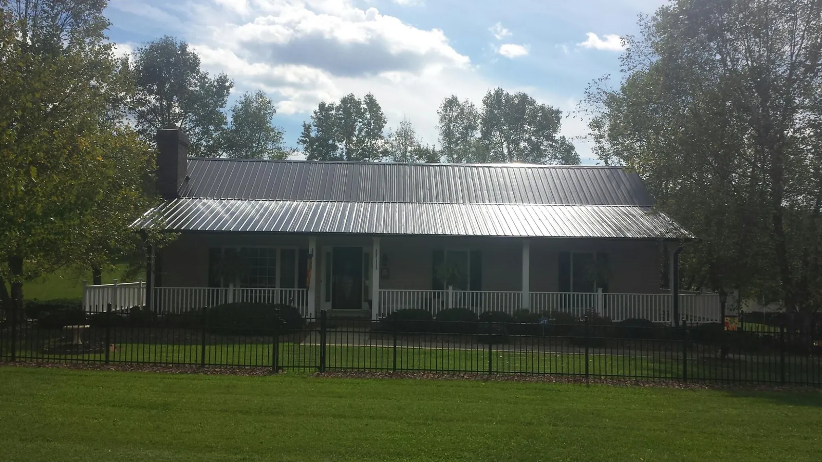 Gray metal roof on a brick ranch with a full width front porch — Gutter Guard Installation work by our crew in Hopkinsville