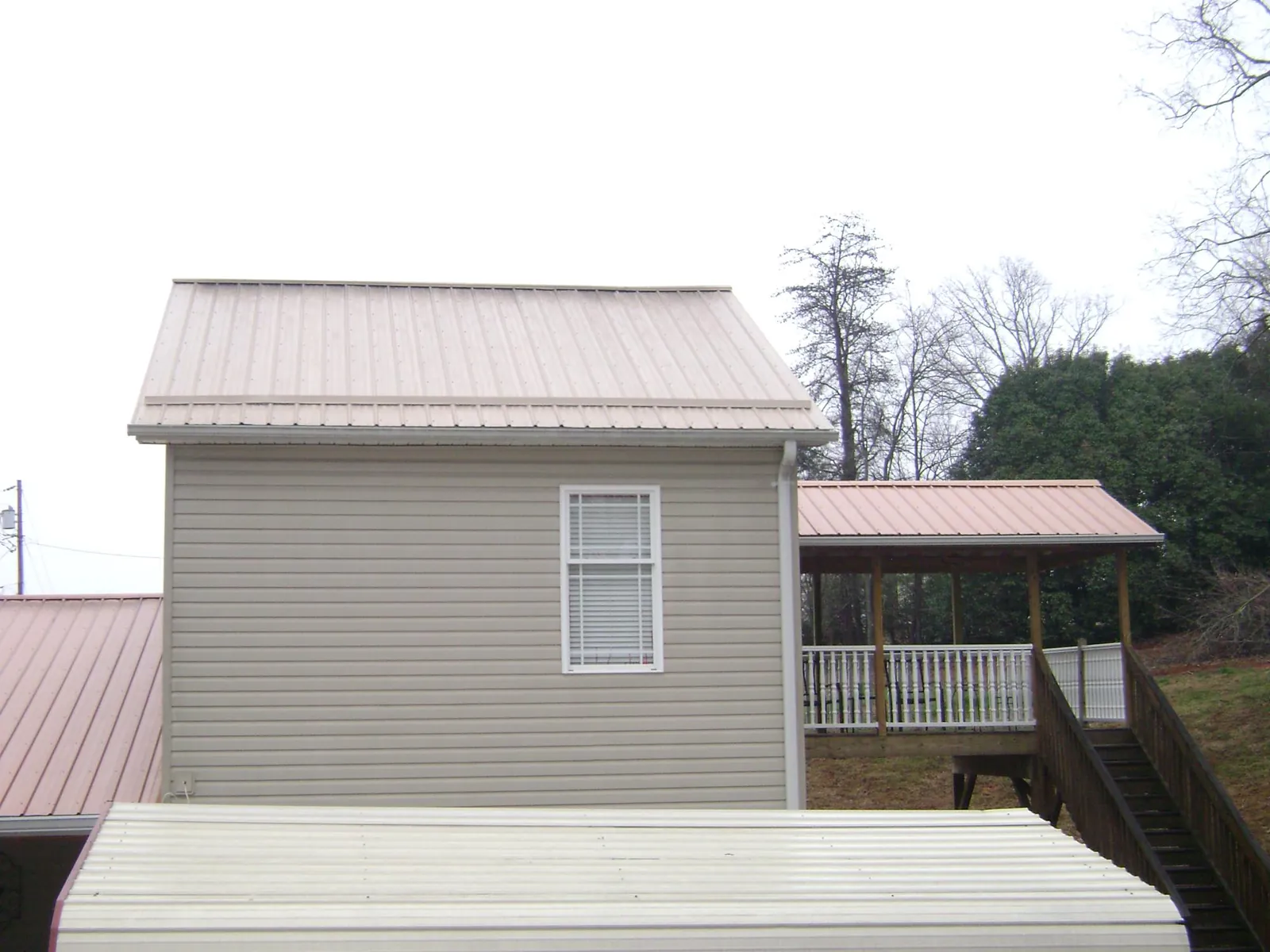 Tan metal roofs on a two story addition and attached porch, from a Roof Replacement job in Hopkinsville