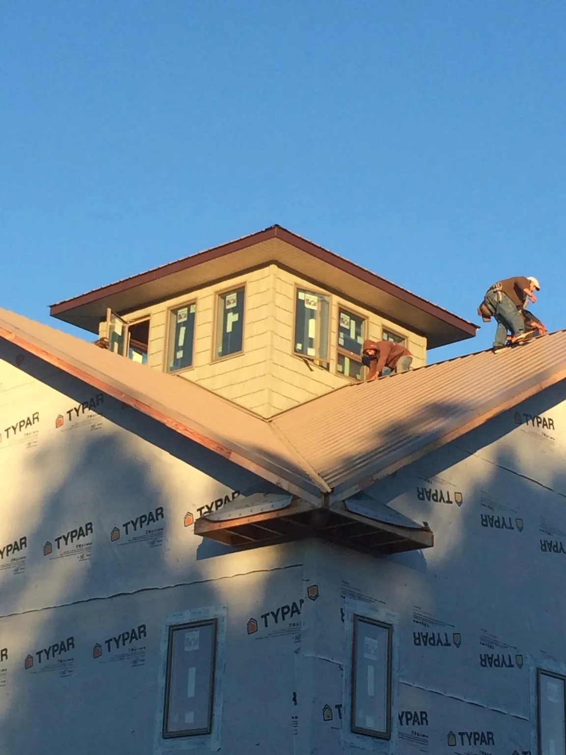 Roofers working around a rooftop cupola on a new metal roof at sunset — Roof Waterproofing in Hopkinsville by Roofing Brothers